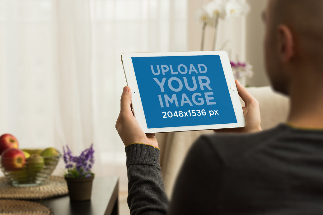 Mockup of a Man Using an iPad Mini in a Comfy Living Room
