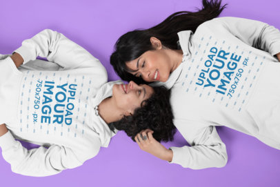 Hoodie Mockup Featuring Two Women Lying on a Flat Surface Looking at Each Other 