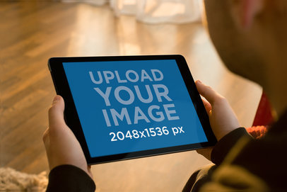 Mockup of a Man Holding an iPad Mini at Home