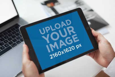 Mockup of a Woman Holding an iPad at Her Desk