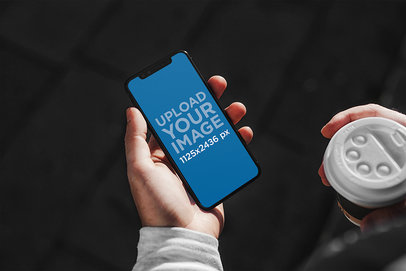 Mockup of a Man With an iPhone 11 in One Hand and a Coffee in the Other