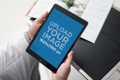 Mockup of a Man Holding an iPad in Portrait Position 