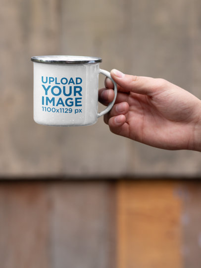 Mockup Featuring a Hand Holding a 12 oz Enamel Mug with a Silver Rim 