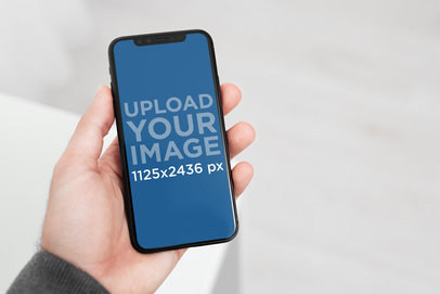 iPhone 11 Pro Mockup Featuring a Man in a Minimalist Room