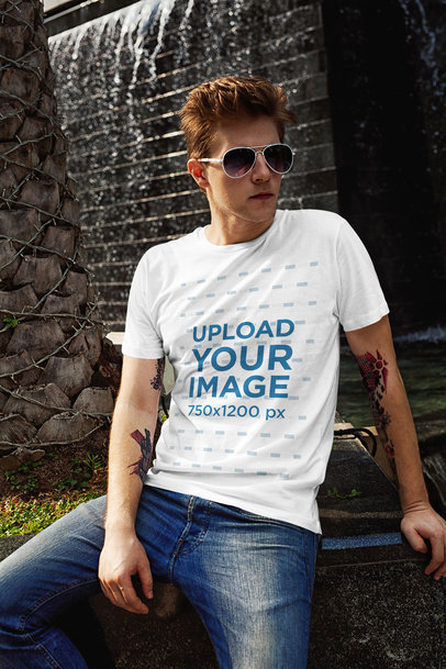 T-Shirt Mockup of a Red-Haired Man Posing Next to a Fountain