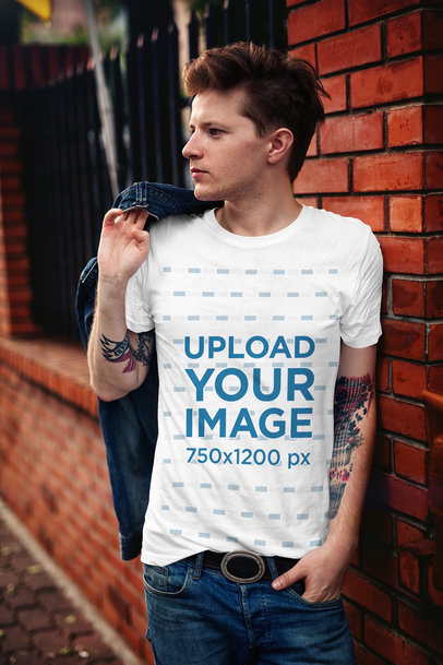 T-Shirt Mockup Featuring a Stylish Man Leaning on a Brick Wall