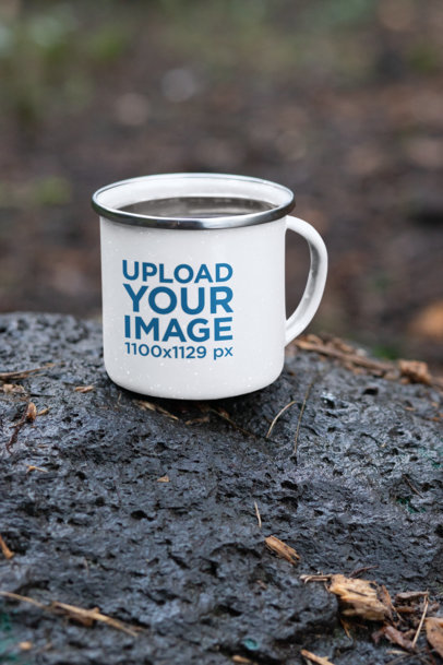 Mockup Featuring a 12 oz Enamel Mug with a Silver Rim Placed on a Rock 