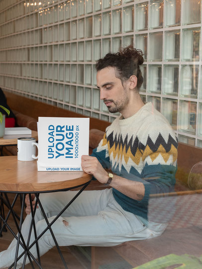 Square Book Mockup Fearing a Man Reading at a Cafe