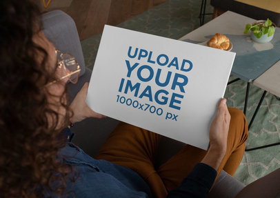 Mockup of a Man Holding a Hardcover Book in His Living Room
