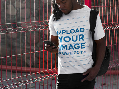 Tee Mockup of a Man With Locs Using His Smartphone