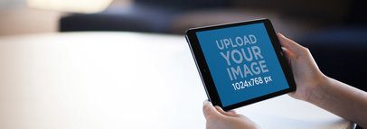 Tablet Mockup of Someone Holding an iPad over a Table