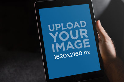 Mockup of a Hand Holding an iPad in a Dark Scenario 