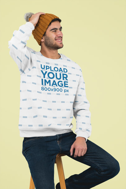 Sublimated Crewneck Sweatshirt Mockup Featuring a Man Sitting on a Stool at a Studio 