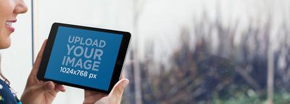 Mockup of an iPad Mini Held With Both Hands by a Smiling Woman