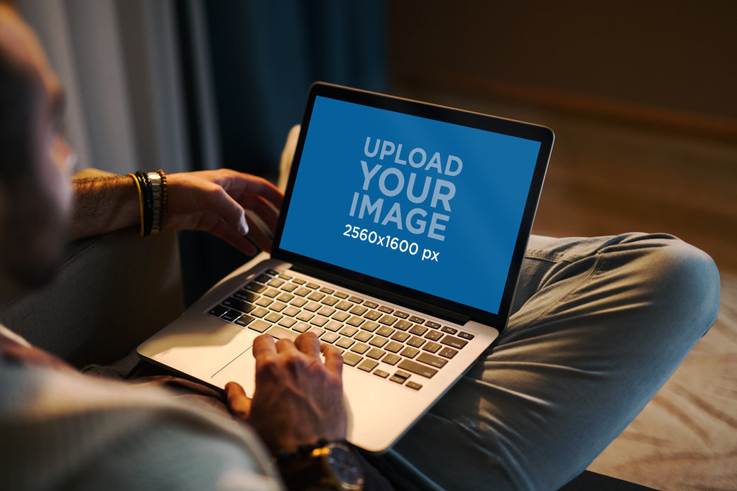 Mockup of a Man Using a MacBook in a Cozy Living Room