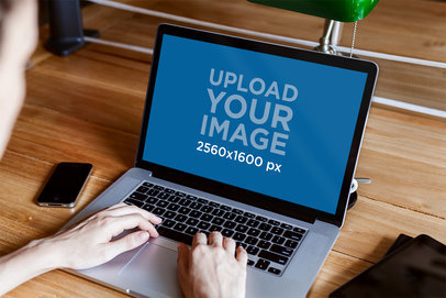 Mockup of a Person Using a MacBook Pro on a Wooden Surface