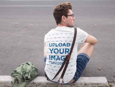 Tee Mockup Featuring a Young Hipster Man Sitting on a Sidewalk