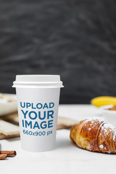 Mockup of a Coffee Cup Next to a Croissant