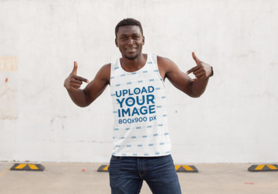 Mockup of a Man Pointing at His Sublimated Tank Top at a Parking Lot