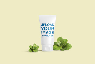 Cosmetic Tube Mockup Featuring Some Mint Leaves and a Plain Background 