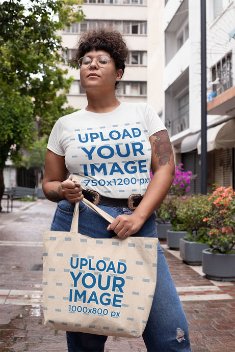 Mockup Featuring a Tattooed Woman in a Plus Size T-Shirt Holding a Tote Bag on the Street
