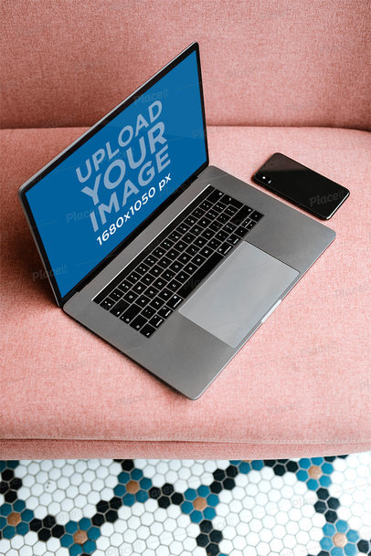 Mockup of a MacBook Next to a Phone on a Pink Sofa