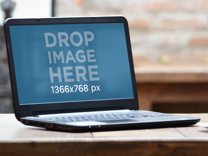 Mockup of a Laptop Placed on a Restaurant's Wooden Table 