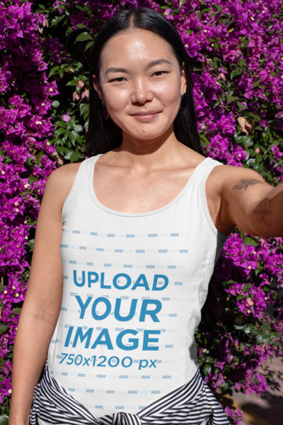 Tank Top Mockup of a Woman Taking a Selfie Against a Bougainvillea