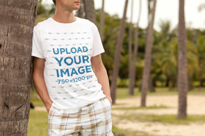 T-Shirt Mockup Featuring a Man Leaning on a Palm Tree