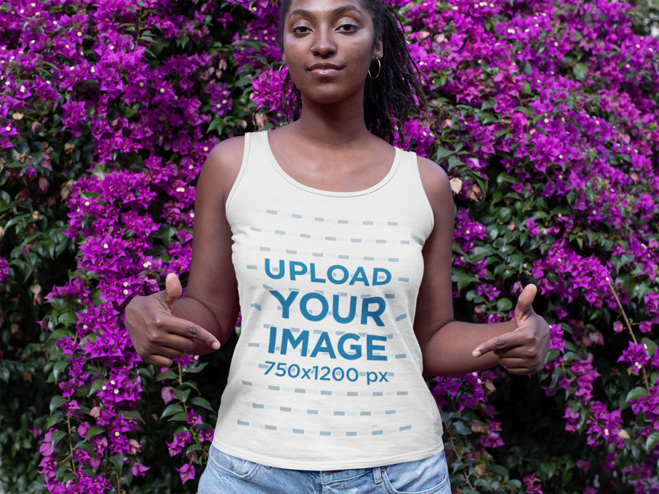 Mockup of a Woman Showing Her Tank Top in Front of a Wall of Flowers