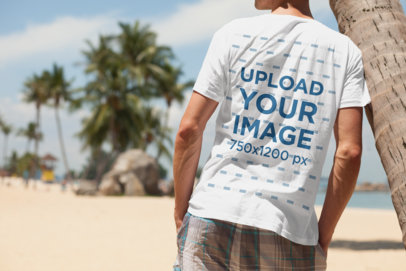 T-Shirt Mockup of a Relaxed Man Leaning on a Palm Tree
