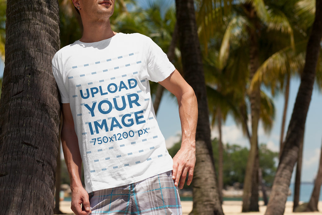 T-Shirt Mockup of a Man at the Beach Leaning on a Palm Tree