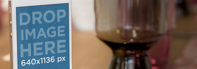 Mockup of an iPhone 5s Gold in Portrait Position Next to a Glass