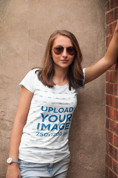 Mockup of a Woman with a Tee Leaning on a Brick Wall 