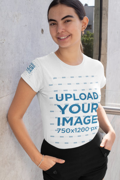 Mockup of a Happy Woman Wearing a T-Shirt with a Customizable Sleeve by a Concrete Wall
