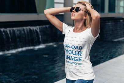 T-Shirt Mockup Featuring a Woman Walking by a Fountain 