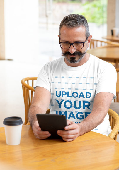 T-Shirt Mockup Featuring a Man Reading at a Cafe
