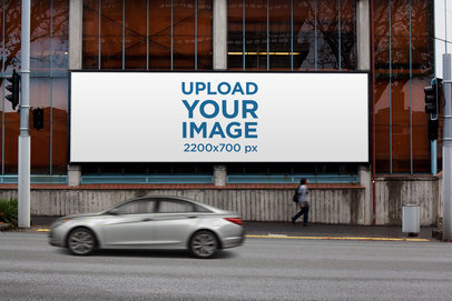 Mockup of a Billboard Placed on a Glass Building by a Street 