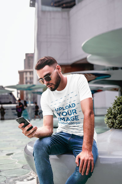 T-Shirt Mockup of a Cool Man Staring at His Phone in the City