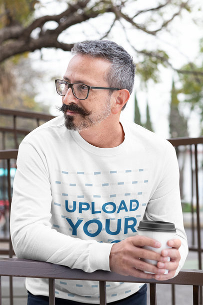 Long Sleeve Tee Mockup of a Man Casually Leaning on a Fence with a Coffee in His Hands