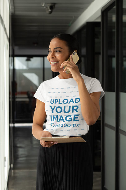 T-Shirt Mockup of a Woman Speaking on the Phone at an Office Hallway