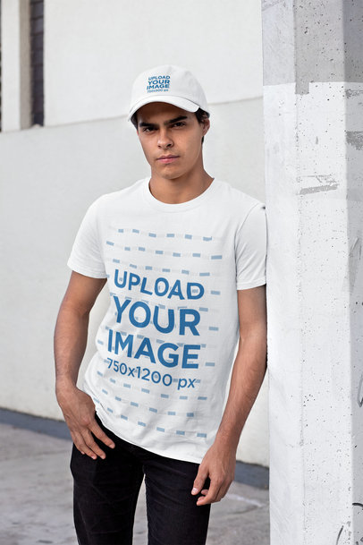 Tee Mockup Featuring a Man with a Dad Hat Leaning Against a Light Pole 