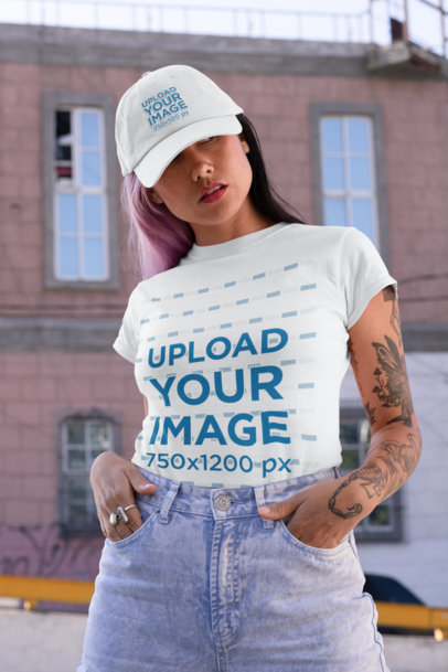 Tee Mockup of a Woman with a Tattooed Arm Wearing a Dad Hat on the Street 