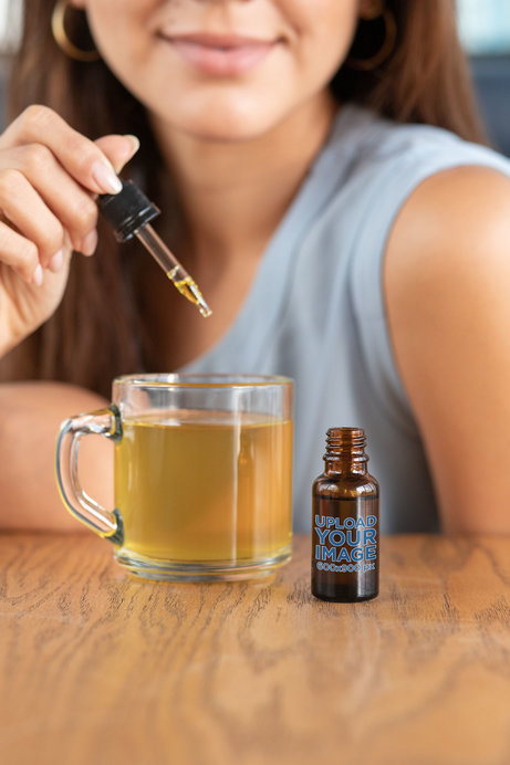 Dropper Mockup Featuring a Woman Adding CBD Drops to Her Tea 