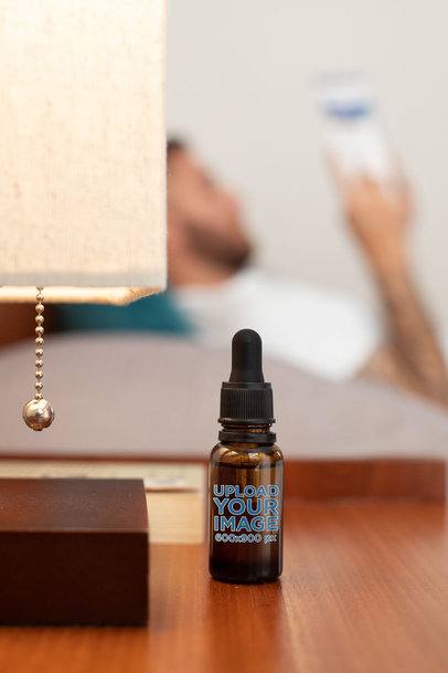 CBD Oil Dropper Bottle Mockup with a Man Reading in the Background