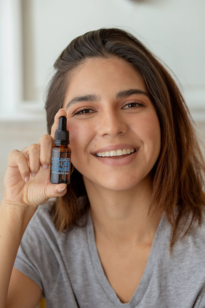 Mockup of a Woman Presenting a CBD Oil Dropper Bottle 