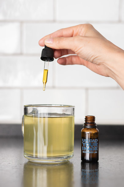 Dropper Mockup Featuring a Woman Adding Some CBD Drops to Her Tea 
