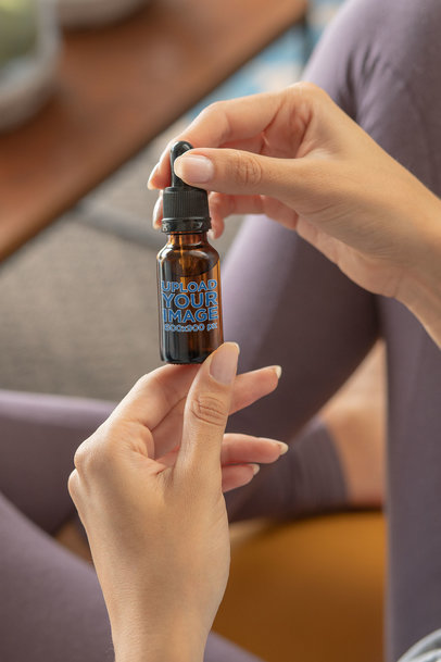 Mockup of a Woman Holding a Dropper Bottle 