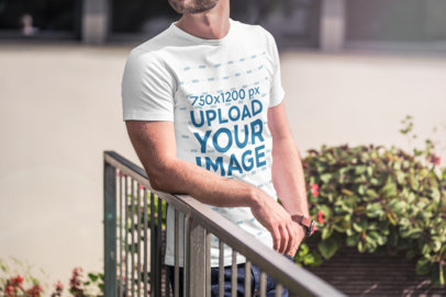T-Shirt Mockup of a Man Casually Standing by a Fence 