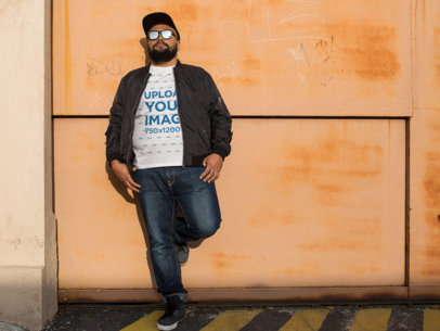 T-Shirt Mockup of a Plus Size Urban Style Guy Leaning Against a Wall